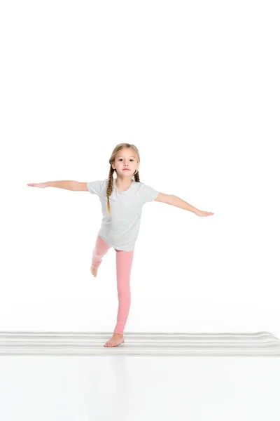 Bonito criança praticando ioga no tapete de ioga isolado no branco — Fotografia de Stock