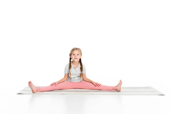 Adorabile bambino che si estende su tappetino yoga isolato su bianco — Foto stock