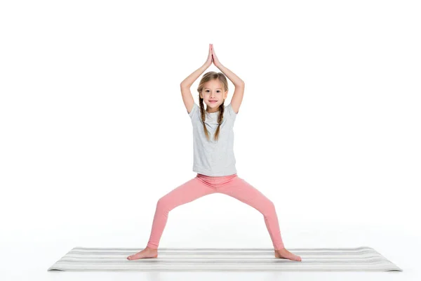 Ребенок практикует йогу на коврике йоги изолированы на белом — стоковое фото