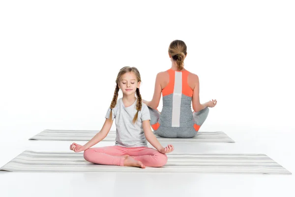 Athletic mother and daughter practicing yoga on mats together isolated on white — Stock Photo