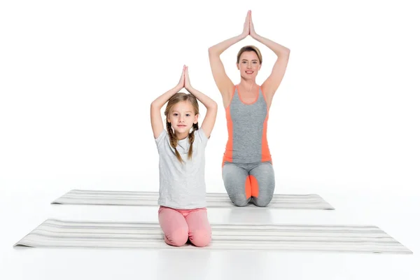 Athletic mother and daughter practicing yoga on mats together isolated on white — Stock Photo