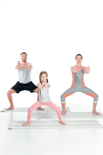 Спортивна сім'я практикує йогу на килимках разом ізольовані на білому — стокове фото