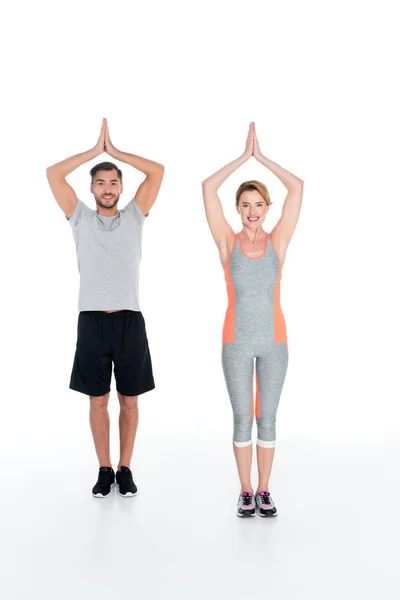 Smiling couple in sportswear practicing yoga isolated on white — Stock Photo