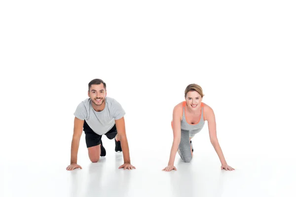 Sonriente deportivo pareja ejercicio juntos aislado en blanco - foto de stock