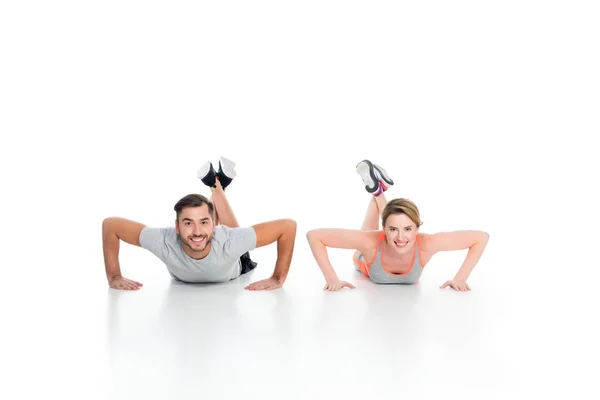 Alegre casal atlético fazendo flexões juntos isolado no branco — Fotografia de Stock
