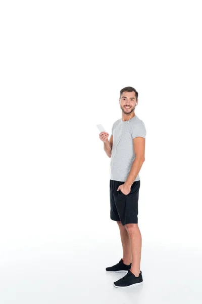 Homme souriant en vêtements de sport et écouteurs écouter de la musique isolée sur blanc — Photo de stock
