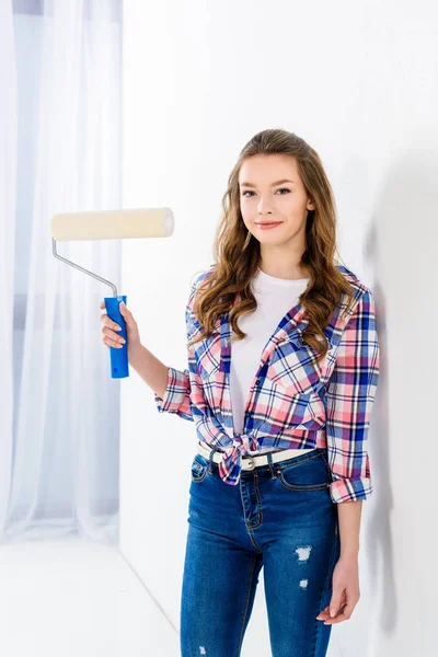Smiling girl holding paint roll brush and looking at camera — Stock Photo
