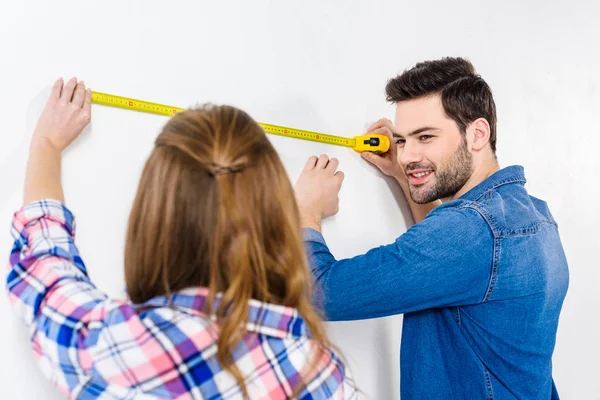 Girlfriend and boyfriend measuring wall with tape measure — Stock Photo