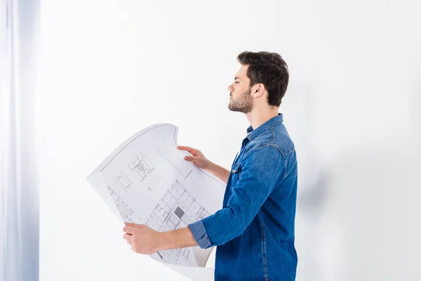 Handsome architect holding blueprint and looking away — Stock Photo