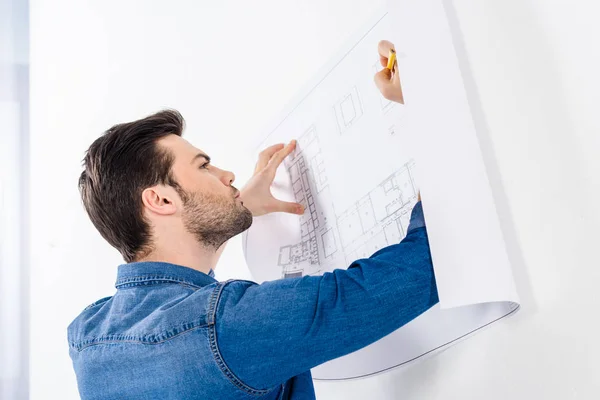 Handsome architect writing on blueprint on white — Stock Photo