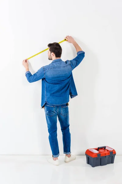 Vue arrière du mur de mesure homme avec ruban à mesurer sur blanc — Photo de stock