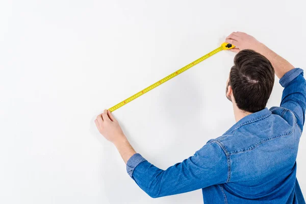 Vista trasera de la pared de medición del hombre con cinta métrica en blanco - foto de stock