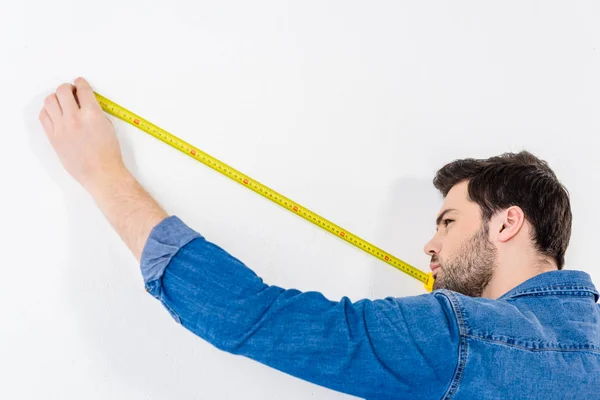 Uomo misura parete con metro a nastro su bianco — Foto stock