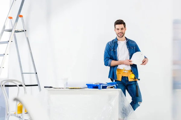 Bel lavoratore sorridente in piedi con casco — Foto stock