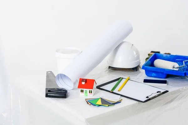 Blueprint with paint roll brush and helmet on table — Stock Photo