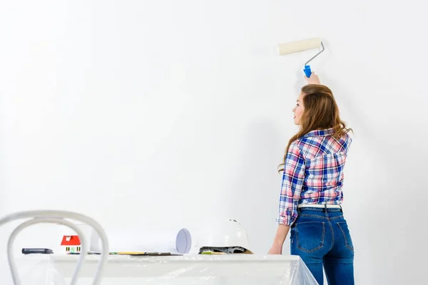 Rear view of girl painting wall with white paint — Stock Photo