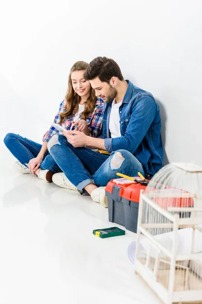 Lächelndes Paar auf dem Boden sitzend und mit Tablet — Stockfoto