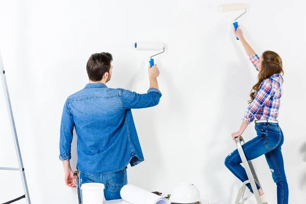 Rear view of couple painting wall with white paint — Stock Photo