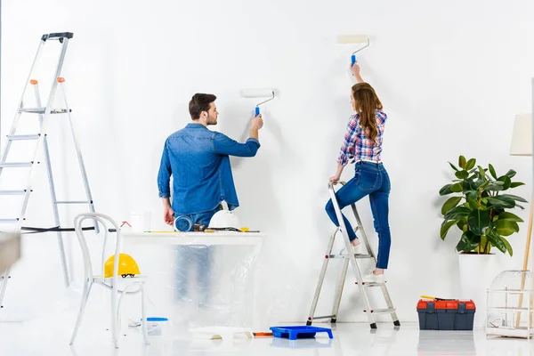 Rear view of couple painting wall with white paint — Stock Photo