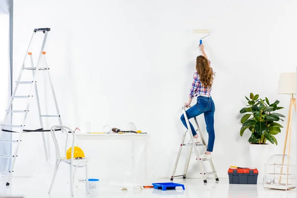 Vista trasera de la niña de pie en la escalera y la pared de pintura - foto de stock