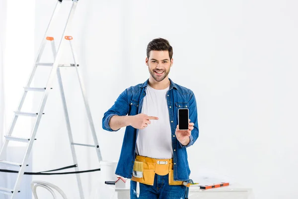 Mann zeigt auf Smartphone und blickt in Kamera — Stockfoto