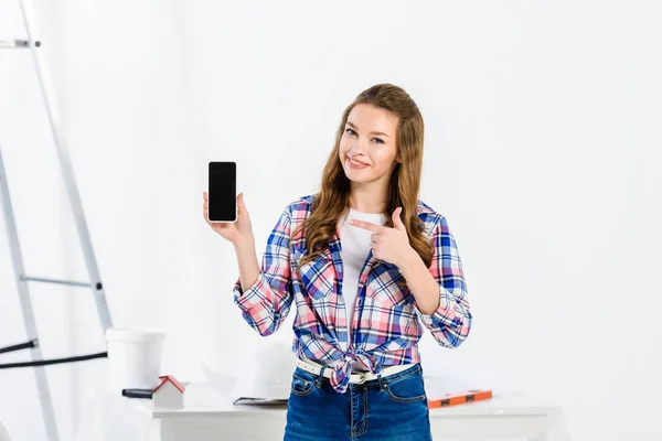 Girl pointing on smartphone and looking at camera — Stock Photo