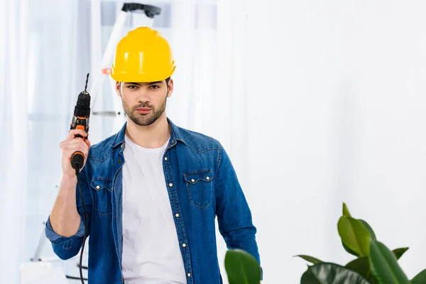 Schöner Mann, der mit Bohrer steht und in die Kamera schaut — Stockfoto