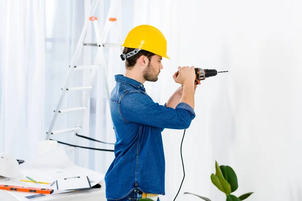 Side view of handsome man using drill and making repairs — Stock Photo