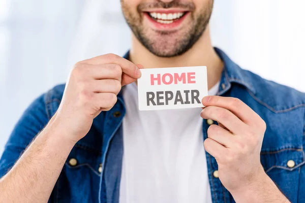 Imagem cortada de homem bonito sorridente segurando cartão de reparação em casa — Fotografia de Stock