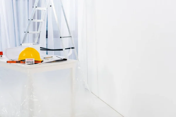 Capacete e cartão de reparação em casa na mesa — Fotografia de Stock