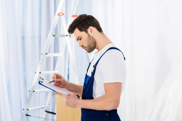 Side view of thoughtful relocation service worker looking at clipboard — Stock Photo