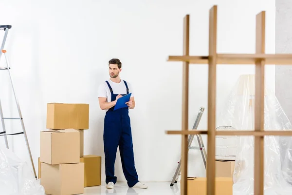 Trabajador de servicios de reubicación guapo de pie con portapapeles - foto de stock