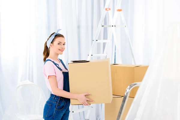 Glückliches Mädchen, das mit Schachtel steht und in die Kamera schaut — Stockfoto