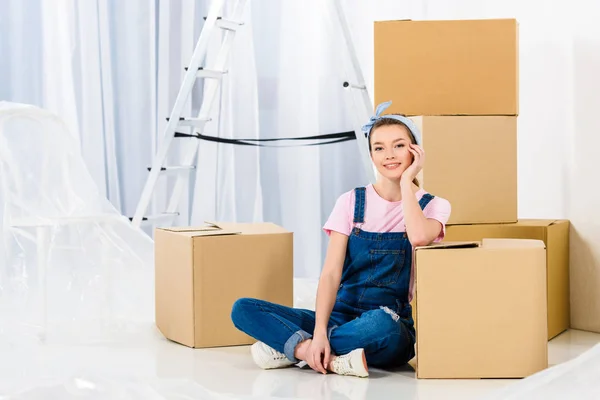 Feliz chica descansando barbilla en la mano y apoyándose en la caja - foto de stock