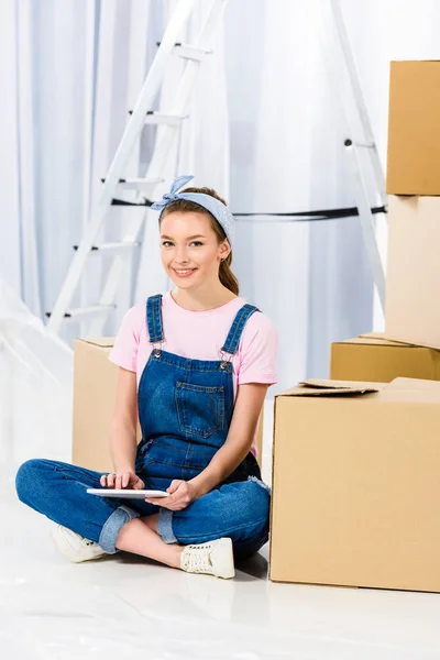 Smiling girl sitting with tablet in new apartment — Stock Photo