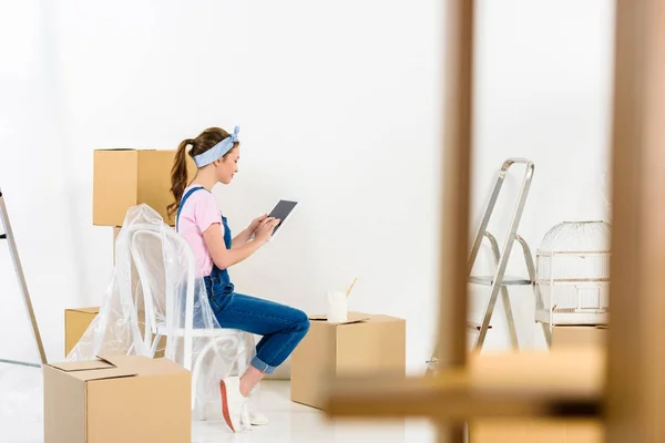 Vista laterale della ragazza utilizzando tablet dopo il trasferimento in una nuova casa — Foto stock