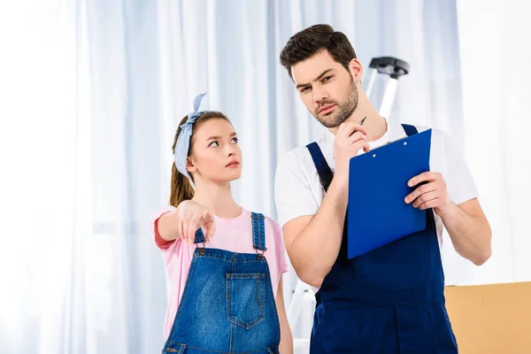 Chica señalando algo a trabajador de servicios de reubicación - foto de stock