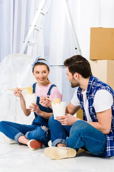 Boyfriend and girlfriend eating noodles in new house — Stock Photo