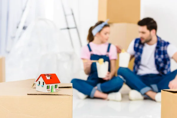 Boyfriend and girlfriend eating noodles with small house on foreground — Stock Photo