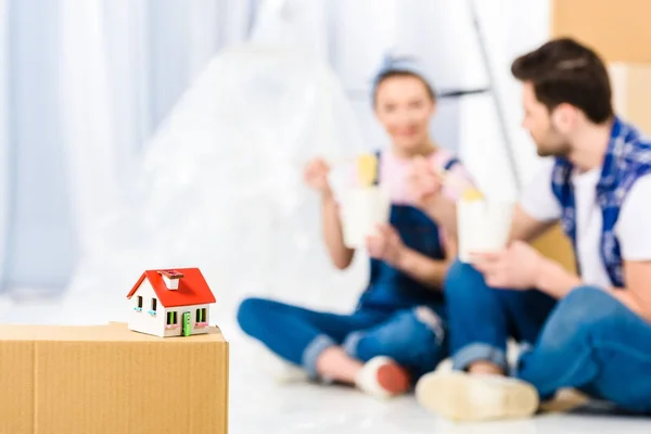 Namorado e namorada comer macarrão com pequena casa em primeiro plano — Fotografia de Stock