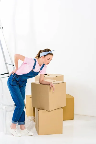 Girl with pain in back after moving heavy boxes — Stock Photo