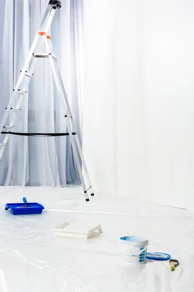 Escada e pincel de rolo de pintura em tinta azul — Fotografia de Stock