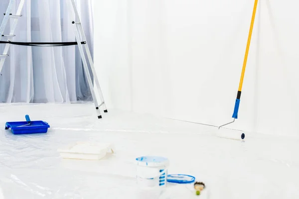 Ladder and paint roller brushes in blue paint — Stock Photo