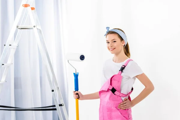 Sorrindo menina de pé com pincel de rolo de pintura — Fotografia de Stock