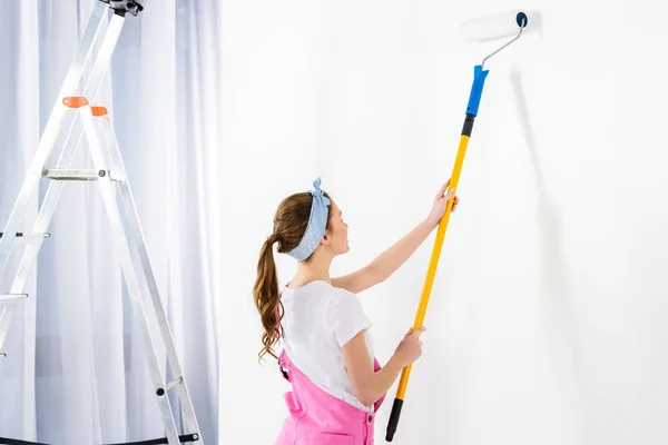 Chica pintura pared con pintura blanca - foto de stock