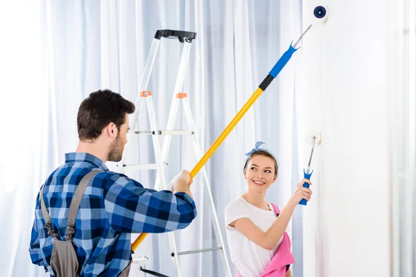 Boyfriend and girlfriend painting wall with white paint — Stock Photo