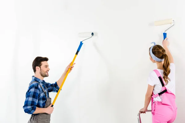 Boyfriend and girlfriend painting wall with white paint — Stock Photo