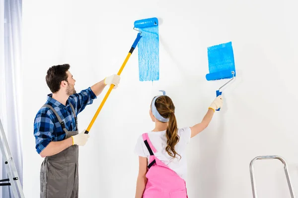 Namorado e namorada parede de pintura com tinta azul — Fotografia de Stock