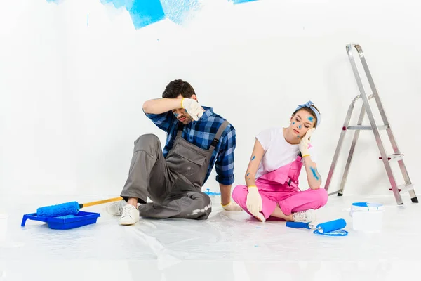Втомлений хлопець і дівчина сидять на підлозі під час ремонту — стокове фото