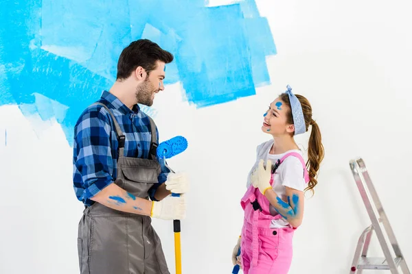 Sonrientes novio y novia mirándose y haciendo reparaciones - foto de stock